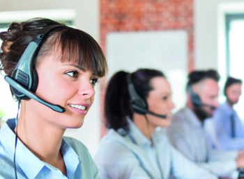 Group of call centre employees take calls on headsets