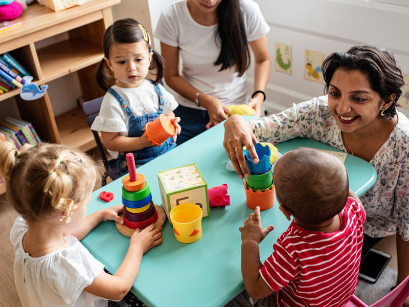 School aged children playing at table with adult