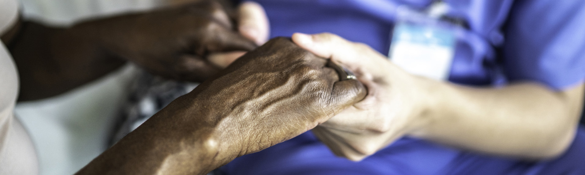 Nursing or retirement home caretaker holding hands with patient