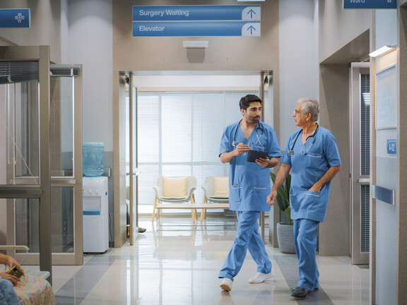 Two male nurses walk through hospital hallway