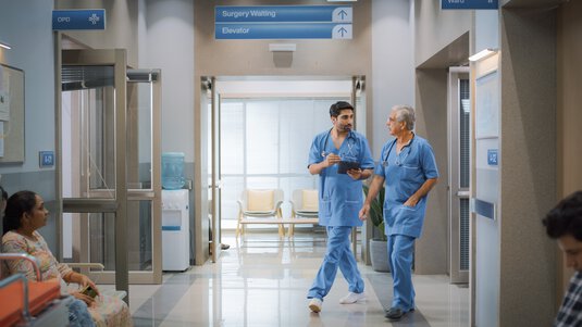Two male nurses walk through hospital hallway